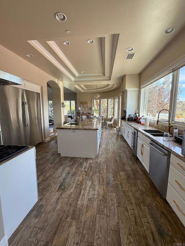 kitchen featuring stainless steel appliances, a raised ceiling, white cabinetry, and a sink