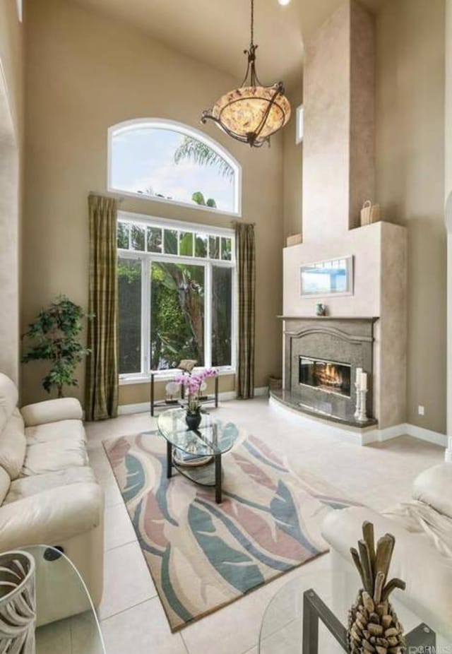 living room with a fireplace, tile patterned flooring, and a towering ceiling