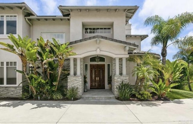 property entrance featuring stone siding and stucco siding