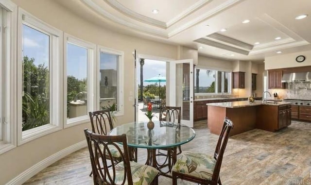 dining space with light wood-style flooring, recessed lighting, baseboards, ornamental molding, and a raised ceiling