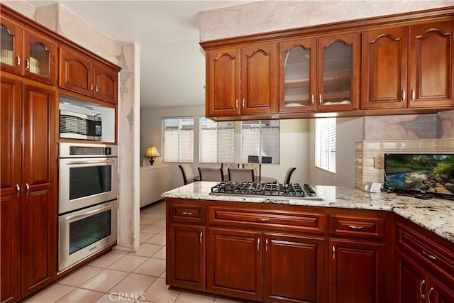 kitchen featuring stainless steel appliances, a healthy amount of sunlight, and light stone countertops