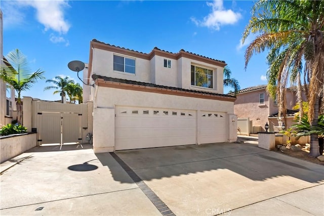 mediterranean / spanish-style house featuring stucco siding, concrete driveway, a gate, a garage, and a tiled roof