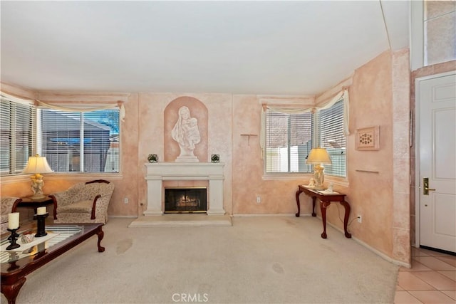 living area featuring carpet floors, a glass covered fireplace, and baseboards