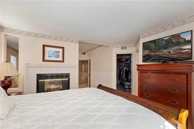 bedroom with a glass covered fireplace, a closet, visible vents, and a spacious closet