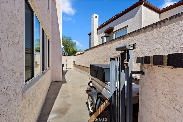 view of side of property with a patio area, fence, and stucco siding