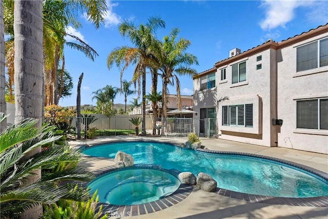 view of swimming pool with a patio area, fence, and a pool with connected hot tub