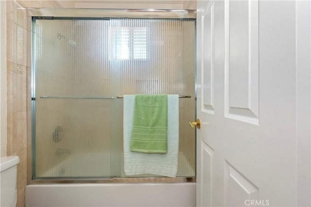 bathroom featuring enclosed tub / shower combo and toilet