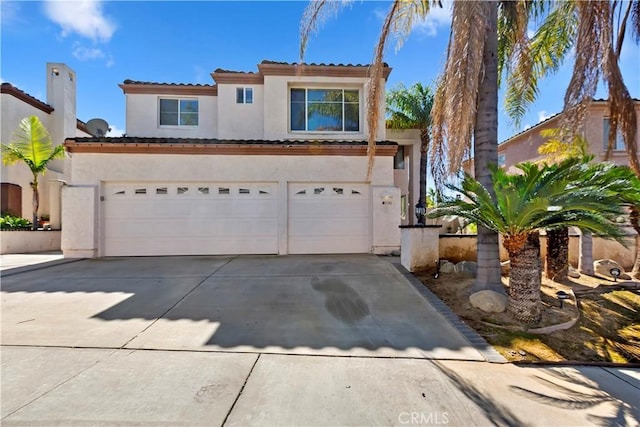 mediterranean / spanish-style house with driveway, an attached garage, a tile roof, and stucco siding