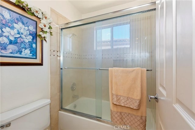 full bath featuring toilet and bath / shower combo with glass door