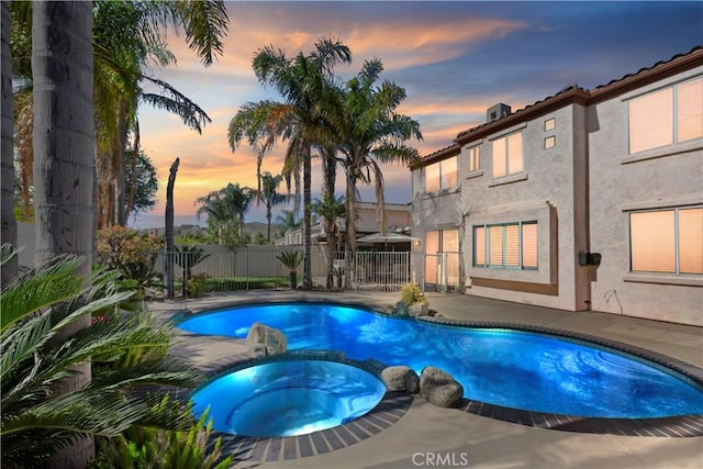 view of swimming pool with a patio area, a pool with connected hot tub, and fence