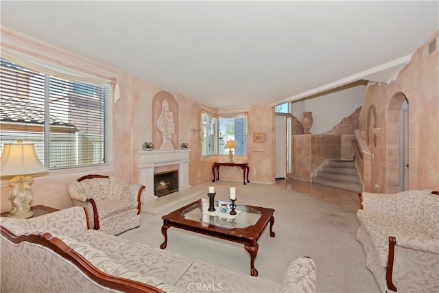 living area with carpet floors, arched walkways, a large fireplace, and stairway