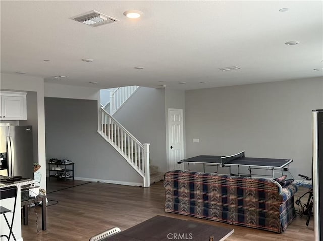 living room featuring stairway, wood finished floors, visible vents, and baseboards