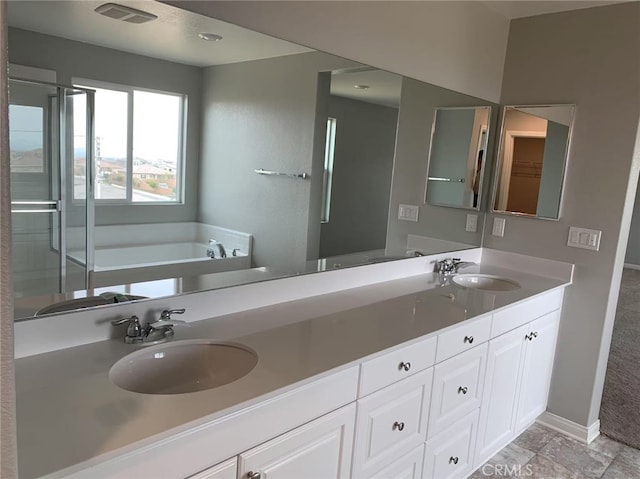 full bathroom with double vanity, a garden tub, visible vents, and a sink