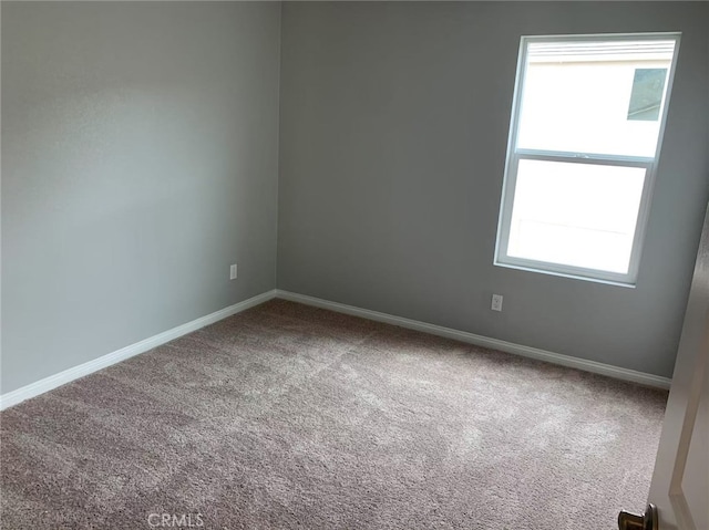 spare room featuring carpet flooring and baseboards