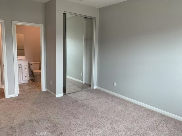 unfurnished bedroom featuring a closet, carpet flooring, baseboards, and ensuite bathroom