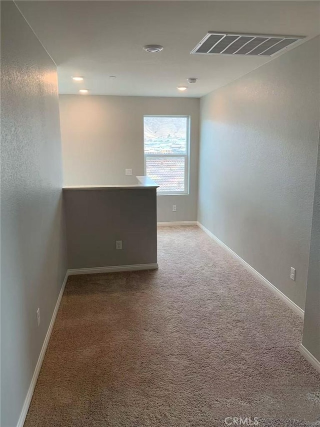 unfurnished room with carpet floors, visible vents, and baseboards