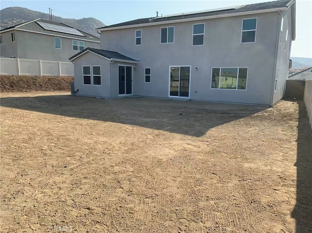 rear view of house with a fenced backyard, a mountain view, and stucco siding