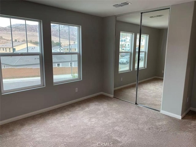 unfurnished bedroom featuring carpet floors, a closet, visible vents, and multiple windows