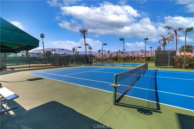 view of tennis court with community basketball court and fence