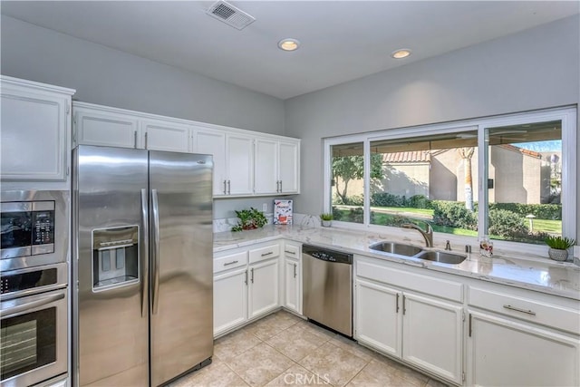 kitchen featuring light stone counters, a sink, visible vents, white cabinets, and appliances with stainless steel finishes