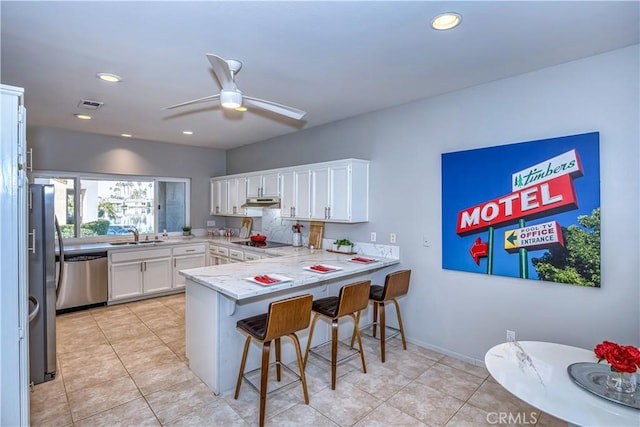 kitchen featuring visible vents, appliances with stainless steel finishes, white cabinetry, a peninsula, and a kitchen breakfast bar