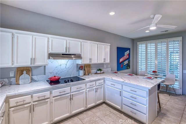 kitchen with black electric stovetop, under cabinet range hood, a peninsula, visible vents, and white cabinets