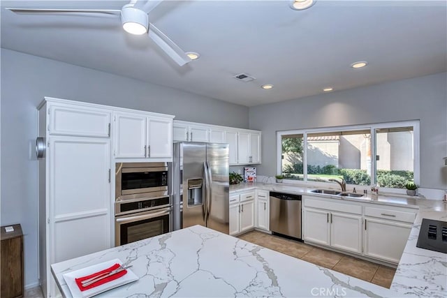 kitchen featuring stainless steel appliances, visible vents, a sink, and light stone counters