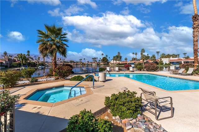 community pool featuring a community hot tub, a patio area, fence, and a water view