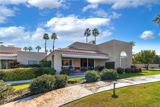 view of front of house featuring a tiled roof, a front lawn, and stucco siding