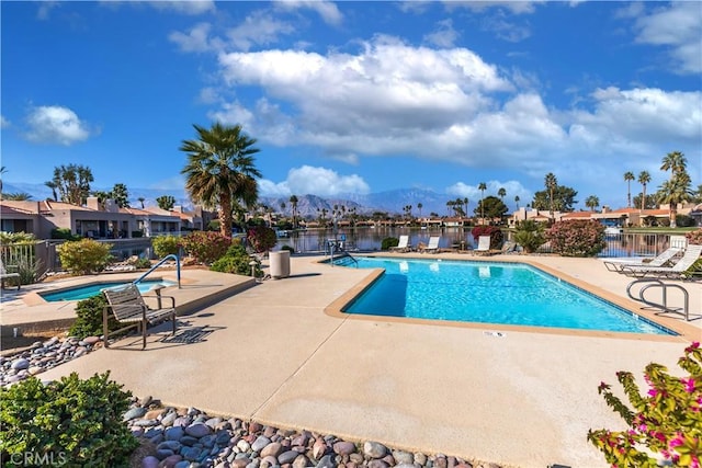 community pool with a mountain view, a patio, and fence