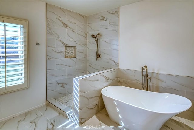 bathroom featuring a sink, marble finish floor, a marble finish shower, and a freestanding bath