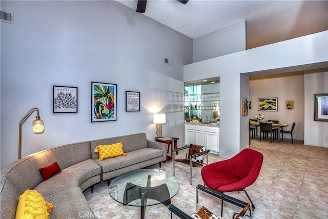 living area featuring visible vents, a towering ceiling, and light tile patterned floors