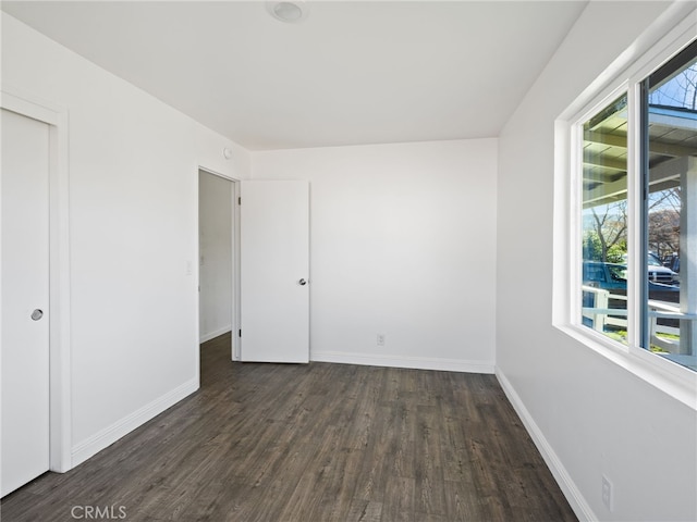 empty room with dark wood-style floors and baseboards