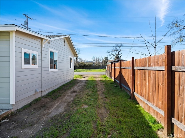 view of yard with dirt driveway and fence