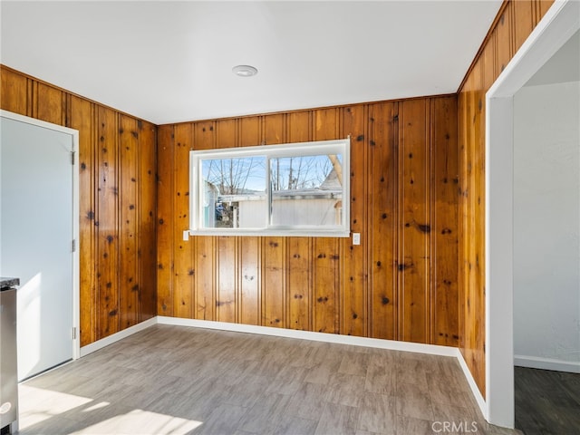 spare room featuring wood walls and baseboards