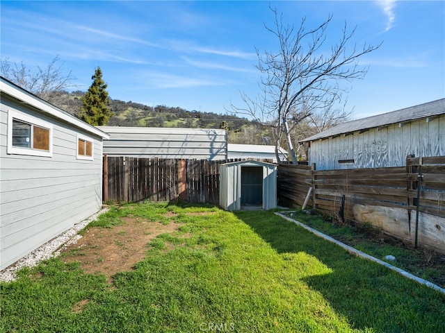 view of yard featuring a fenced backyard, a storage unit, and an outbuilding