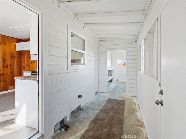 interior space with wood walls and unfinished concrete floors