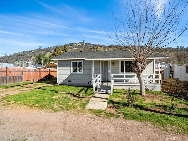 view of front of home featuring a shingled roof, crawl space, fence, a porch, and a front yard