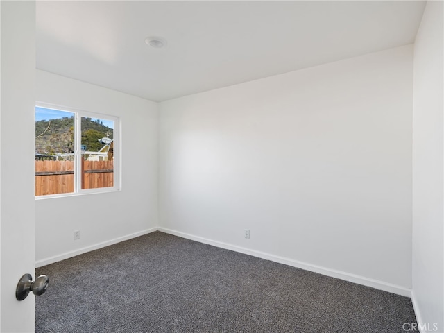 unfurnished room with dark carpet and baseboards