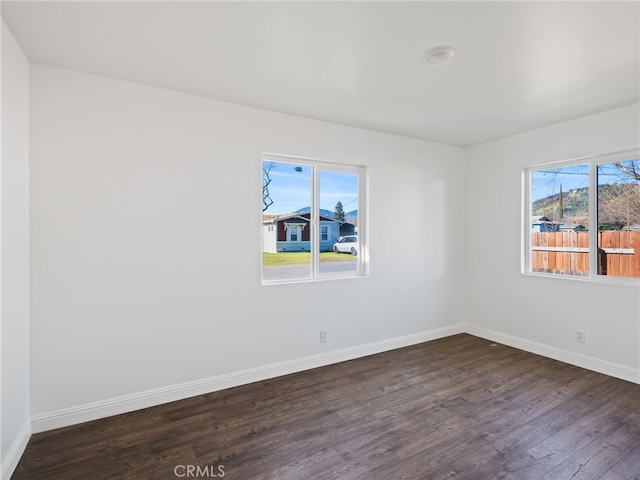 spare room featuring dark wood-style flooring and baseboards