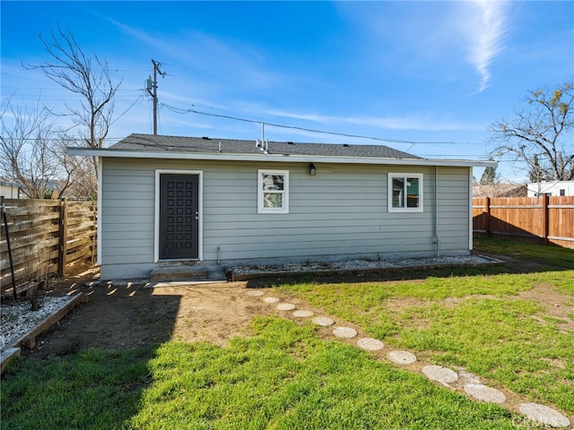 rear view of property featuring a lawn and a fenced backyard