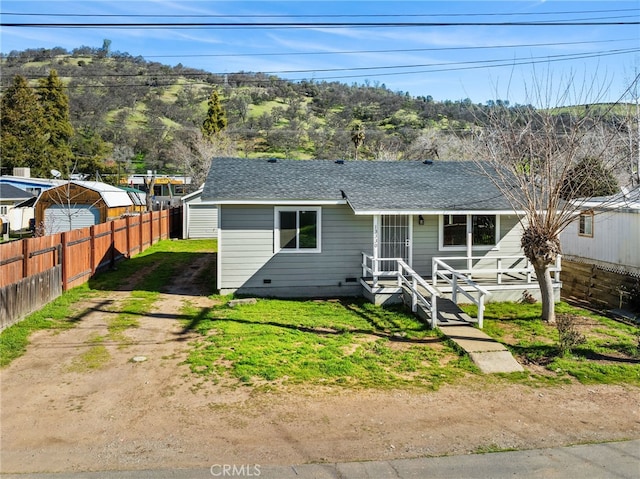 view of front of house featuring a front yard, roof with shingles, fence, and dirt driveway