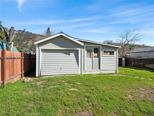 exterior space with a lawn, a garage, a fenced backyard, driveway, and an outdoor structure