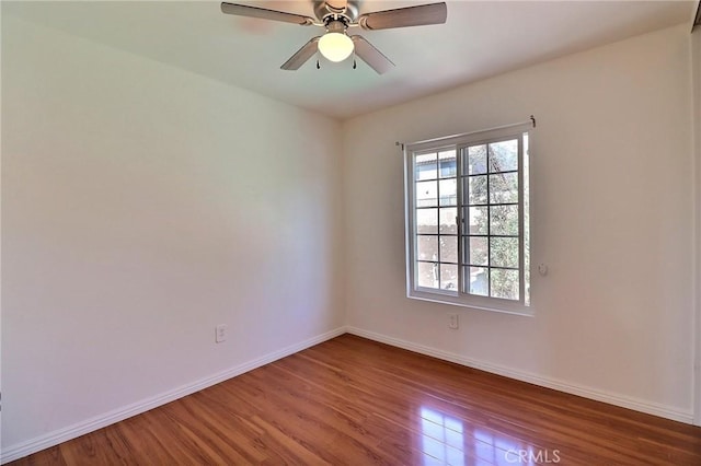 unfurnished room with ceiling fan, wood finished floors, and baseboards