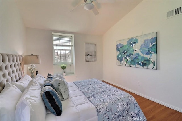 bedroom featuring baseboards, visible vents, vaulted ceiling, and wood finished floors