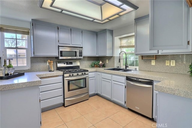 kitchen featuring light countertops, appliances with stainless steel finishes, a sink, and tasteful backsplash