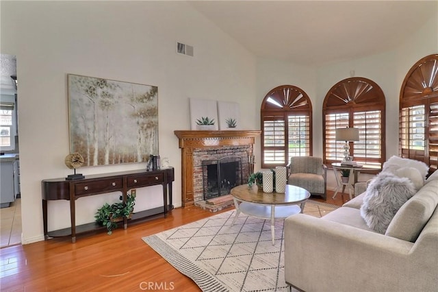 living room featuring visible vents, vaulted ceiling, a fireplace, and wood finished floors