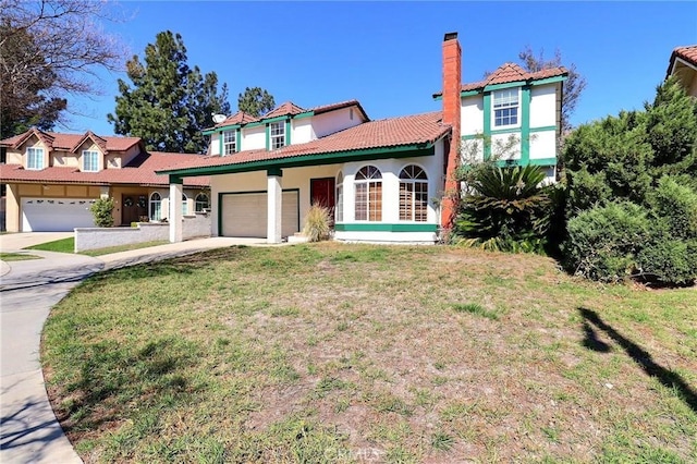 mediterranean / spanish house with a garage, concrete driveway, a chimney, a front yard, and stucco siding