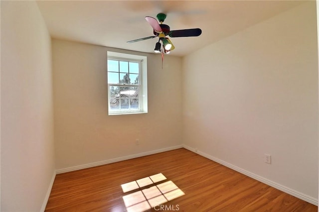 spare room featuring ceiling fan, baseboards, and wood finished floors