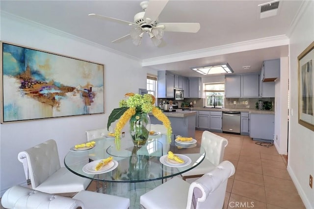 dining space with light tile patterned floors, visible vents, baseboards, ceiling fan, and ornamental molding